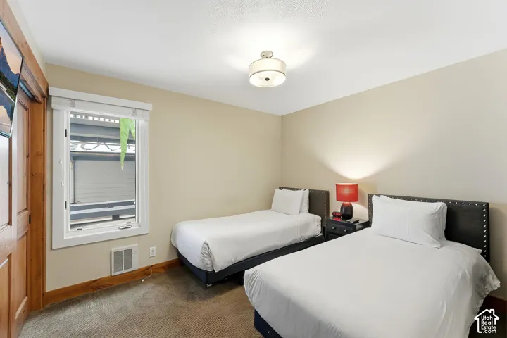 Carpeted flooring with wood-finish trim, window with white framing, and a ceiling-mounted light fixture