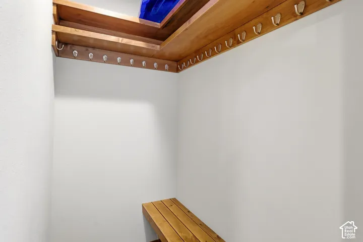 Built-in wood shelving with integrated hooks, wood-slat bench seating, and white painted walls