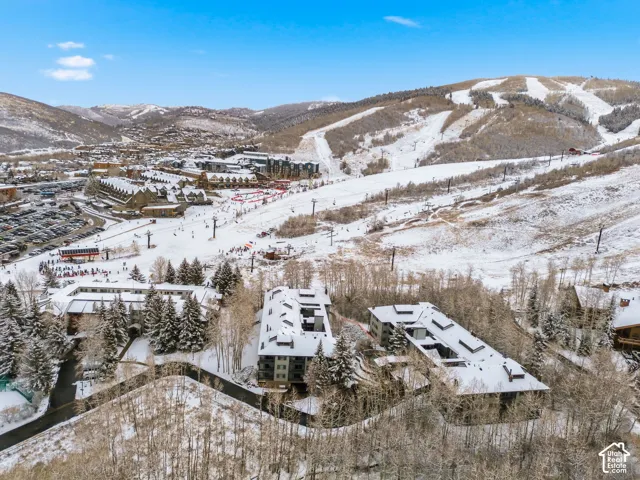 Snow-covered mountain setting with multiple buildings, ski slopes, and wooded areas