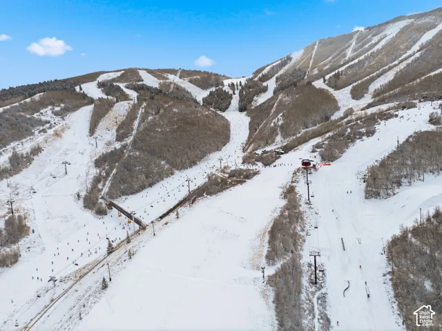 Snow-covered mountainous terrain featuring ski slopes, chairlifts, and a ski bridge