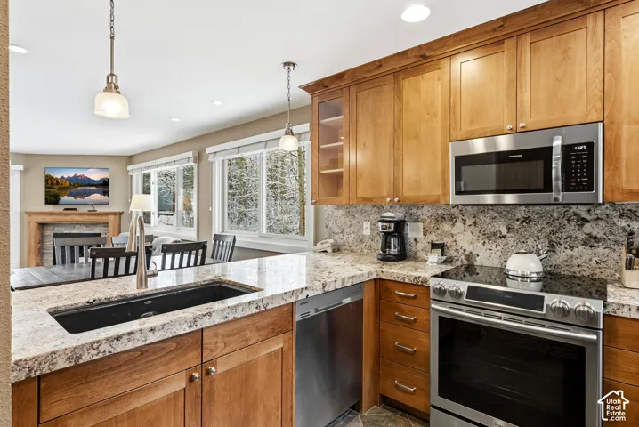 Open-concept kitchen featuring granite countertops, stainless steel appliances, and wood cabinetry