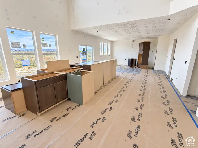 Open-concept interior featuring high ceilings, large windows, and dark wood-finish cabinetry