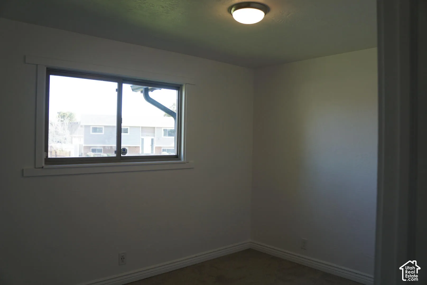 Interior room featuring neutral wall paint, carpeting, a single-pane window with trim, and a flush-mount ceiling light fixture