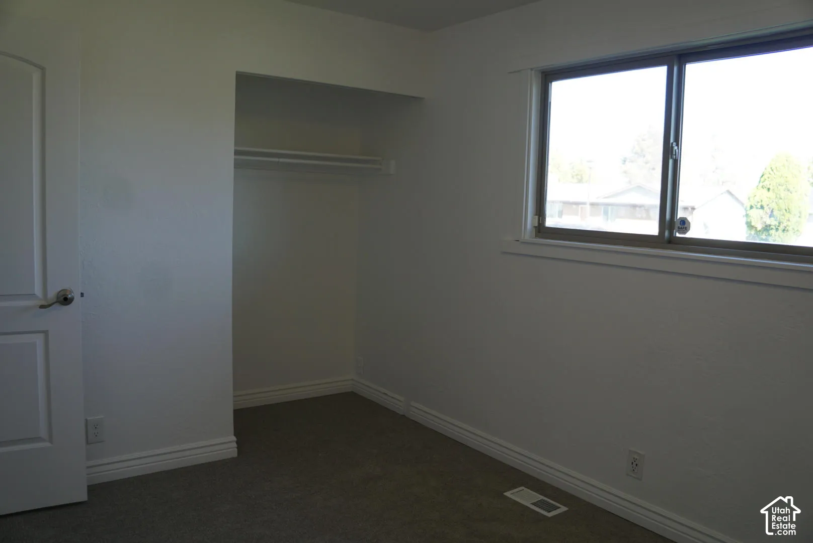 Neutral-toned carpeting, sliding window with metal frame, and built-in closet with overhead shelving