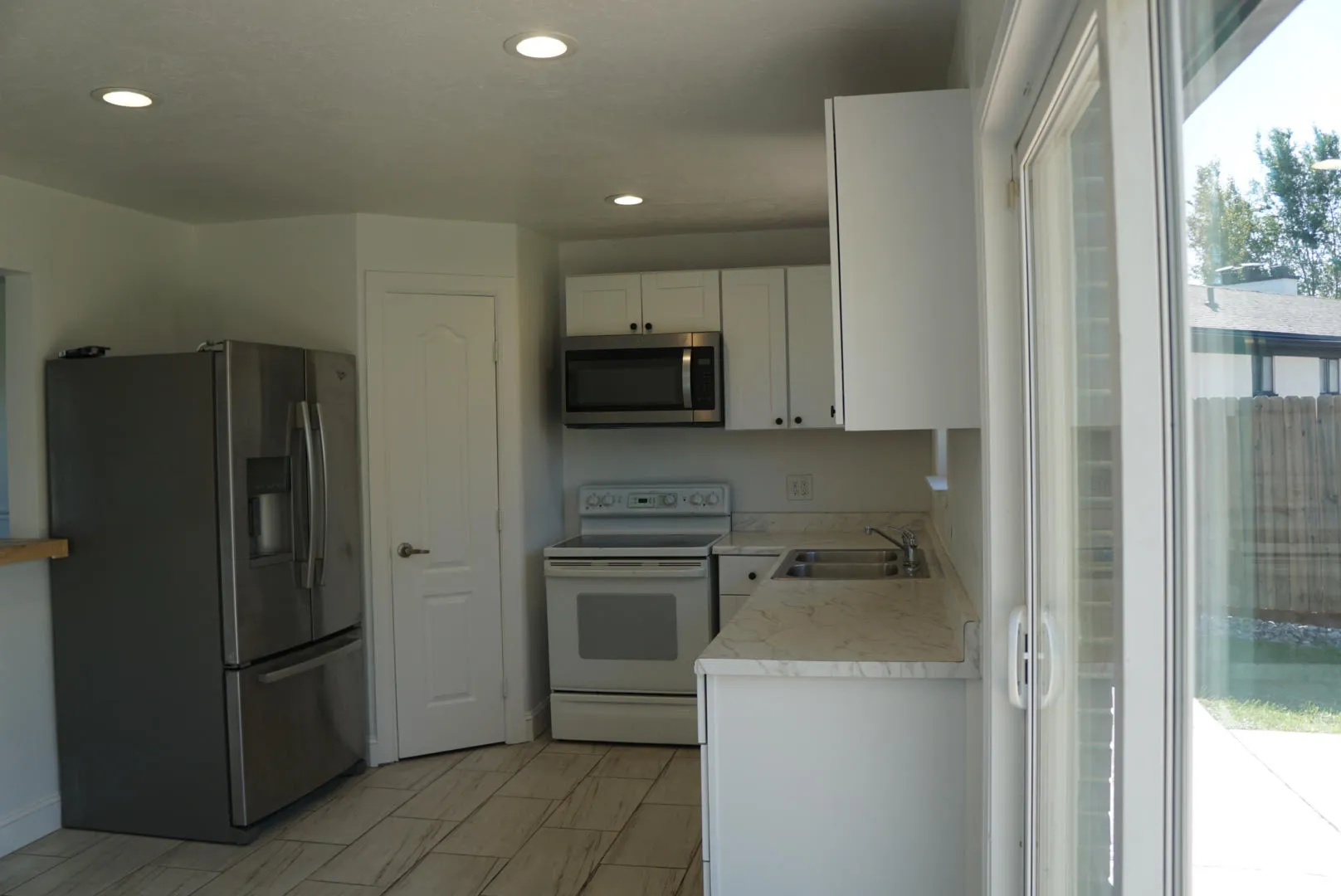 Kitchen featuring white cabinetry, stone-patterned countertops, stainless steel appliances, wood-finish tile flooring, and recessed ceiling lighting