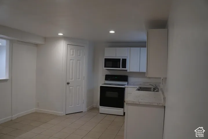 Kitchen featuring white cabinetry, stone-finish countertops, an over-the-range microwave, a built-in range, and tile flooring