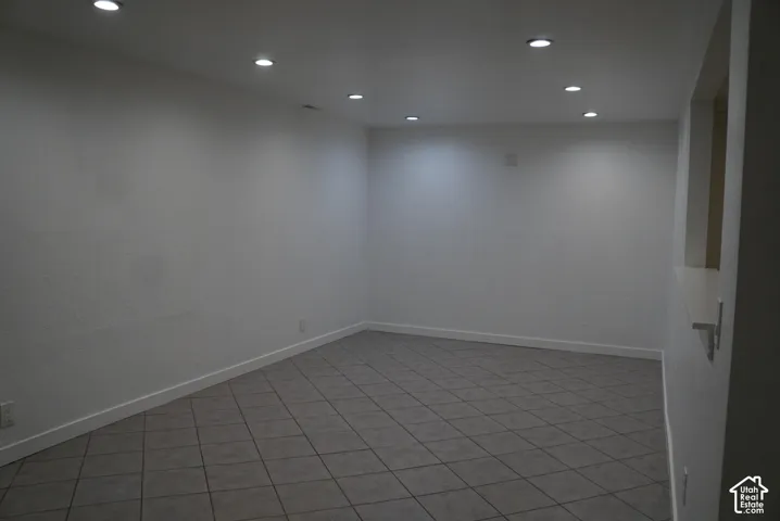 Neutral-toned interior space featuring diamond-pattern ceramic tile flooring, recessed ceiling lighting, and a built-in wall pass-through shelf