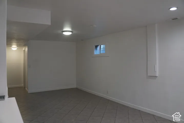 Neutral-toned interior featuring ceramic tile flooring, smooth wall finishes, recessed lighting, and a single egress window