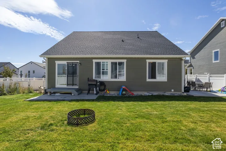 Rear exterior featuring horizontal lap siding, asphalt shingle roof, sliding glass door, concrete patio, and white vinyl privacy fencing