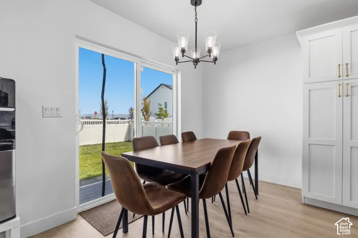 Bright area featuring wood-finish flooring, white floor-to-ceiling cabinetry, a five-light metal chandelier, and a sliding glass door