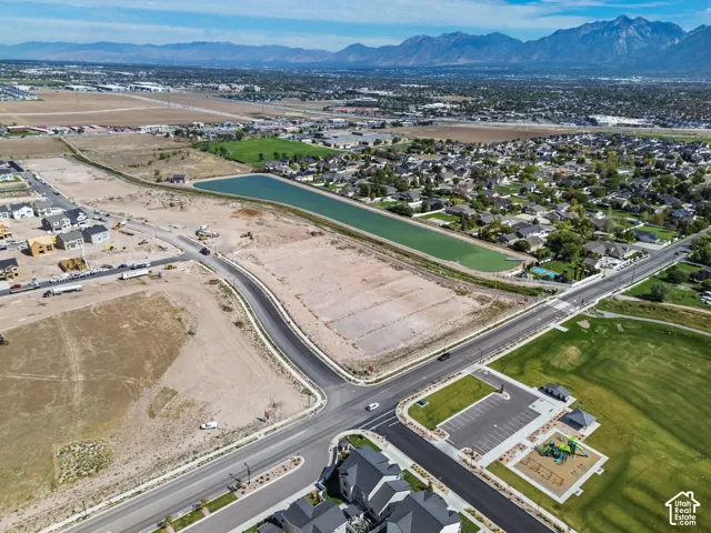 Aerial perspective featuring expansive mountain backdrops, a proximity to a recreational park with paved parking, and a large detention basin