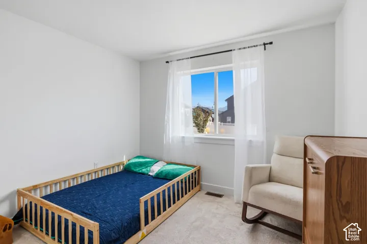 3rd bedroom with neutral-toned walls, carpeting, and a sliding window featuring a sill