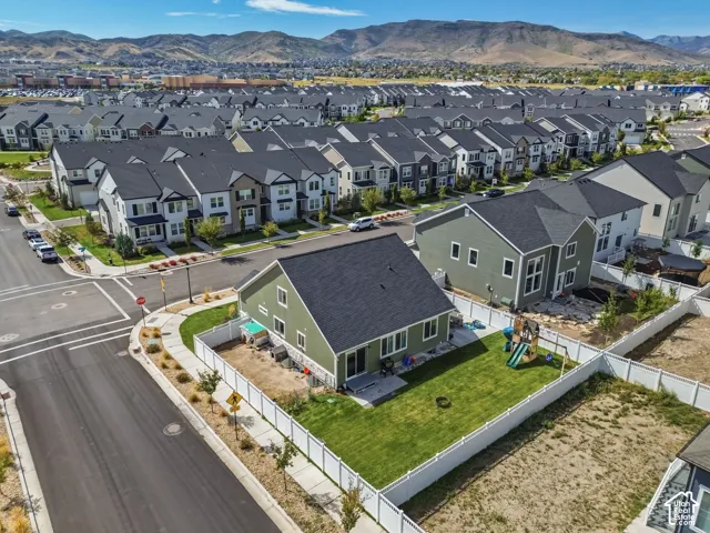 Corner-lot residence featuring a fully fenced backyard, manicured lawn, concrete patio, and stone veneer accents