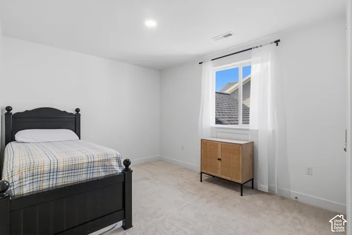 5th Bedroom. Neutral-toned interior space featuring light-colored wall-to-wall carpeting, crisp white walls, and a recessed ceiling light