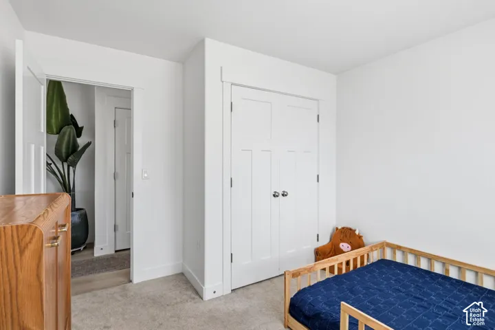 3rd bedroom. Neutral-toned wall-to-wall carpeting, white interior doors with three-panel detailing, and closet featuring matching double doors with round brushed nickel hardware