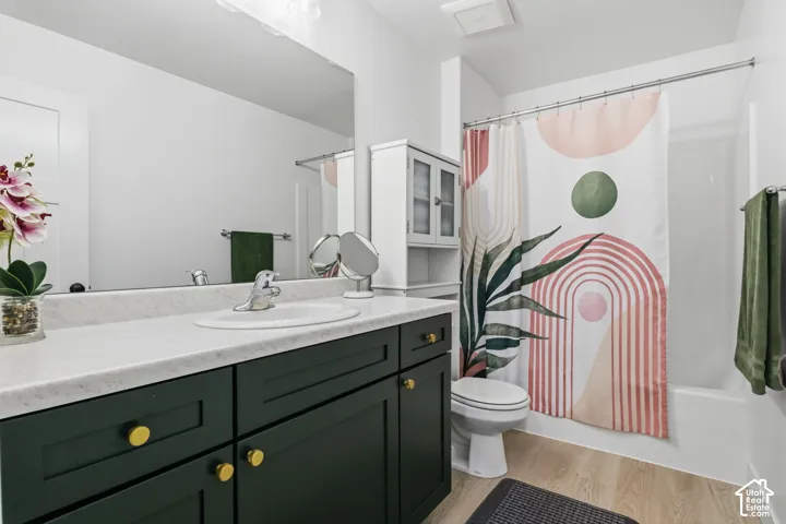 Upstairs Bathroom featuring dark cabinetry with gold-tone hardware, a light-toned solid surface countertop, an undermount sink, and wood-finish flooring