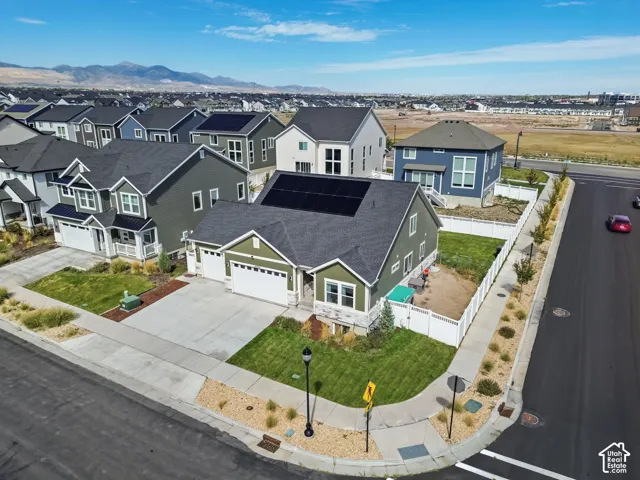 Single-story residence featuring composite shingle roofing, solar panels, attached multi-car garage, stone and siding exterior, and fenced perimeter