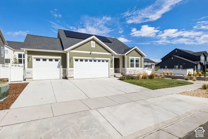 Exterior featuring shingle and horizontal lap siding, stone veneer accents, a three-car garage, and roof-mounted solar panels