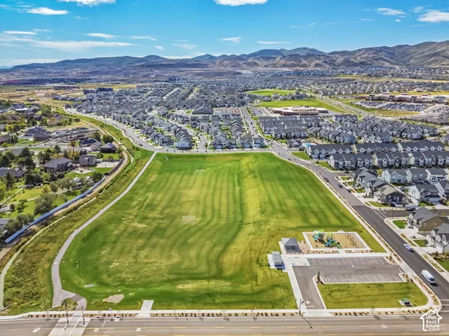Expansive public green space featuring a paved walking path, playground equipment, covered pavilion, and dedicated parking lot