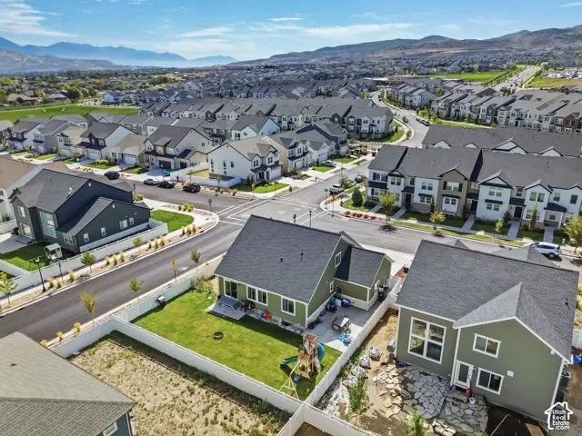 Aerial perspective of residential properties featuring fenced yards, concrete patios, and mountain backdrop