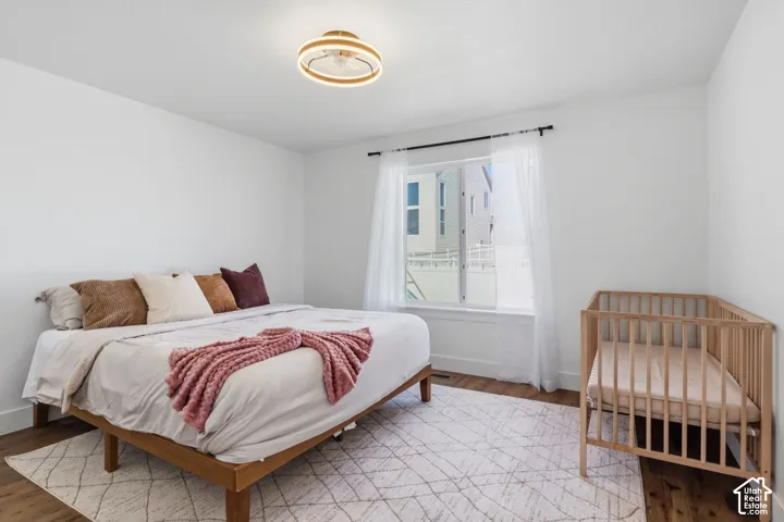 Master Bedroom featuring wood-finish flooring, a contemporary circular flush-mount ceiling fixture, and a large window with a black curtain rod