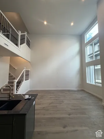 High-ceiling interior featuring a stacked window wall, wood-finish flooring, and a staircase with decorative metal balusters
