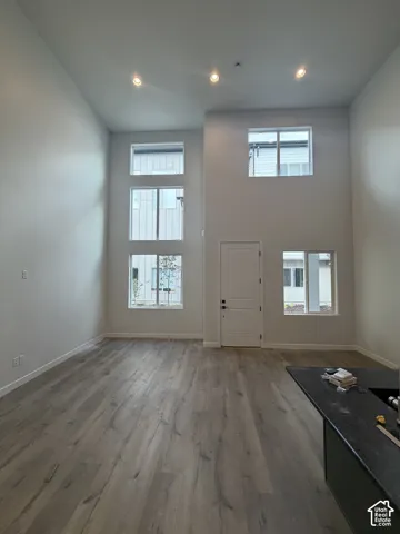Vaulted ceilings, wood-finish flooring, recessed lighting, and multiple windows providing natural illumination, anchored by a dark countertop peninsula