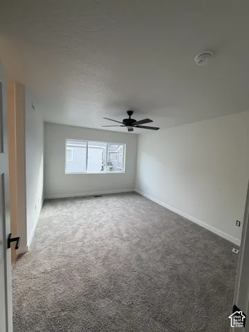 Neutral-toned carpet, matte black ceiling fan, and sliding window with white framing