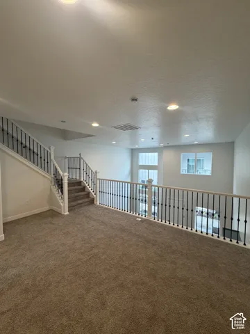 Open landing featuring recessed lighting, metal balusters with a wood-finish handrail, neutral carpeted flooring, and oversized windows