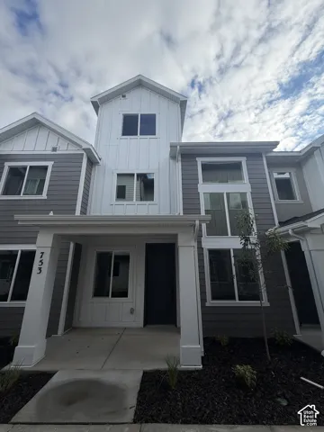 Exterior featuring a mixed-material facade with horizontal siding and vertical paneling, covered entryway with square pillars, and multi-pane windows