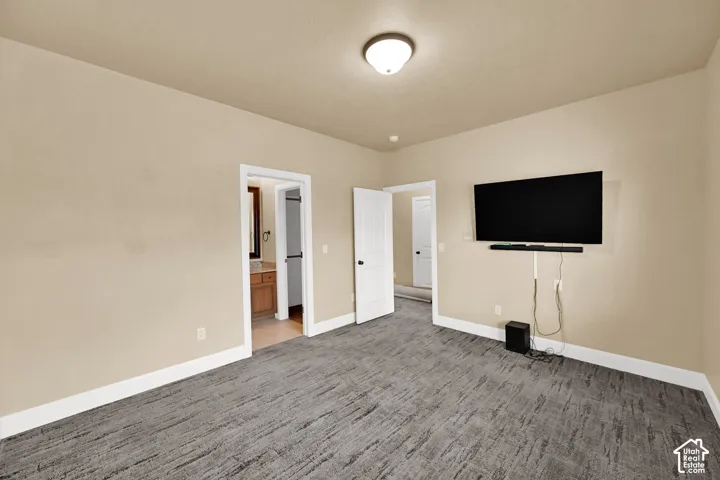 Room featuring grey carpeting, neutral wall paint, and two interior doors with white trim