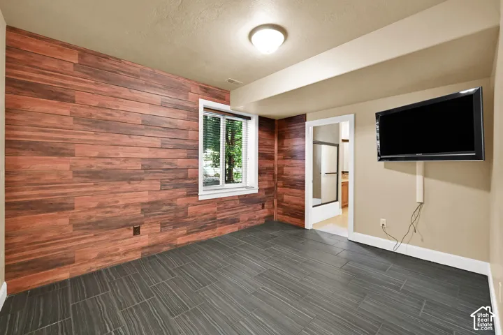 Room featuring wood-finish wall paneling, large-format grey tile flooring, and a flush-mount ceiling light fixture