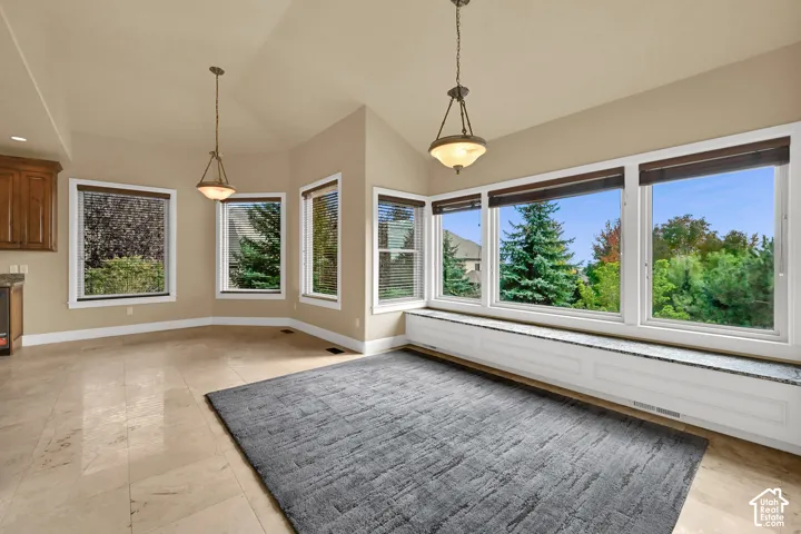 Vaulted ceilings, expansive windows, stone-tile flooring, built-in window seating with stone surfacing, and dual hanging pendant lights