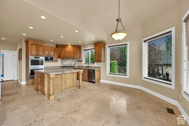 Kitchen featuring stained wood  center island, stone flooring, and integrated stainless steel wall oven