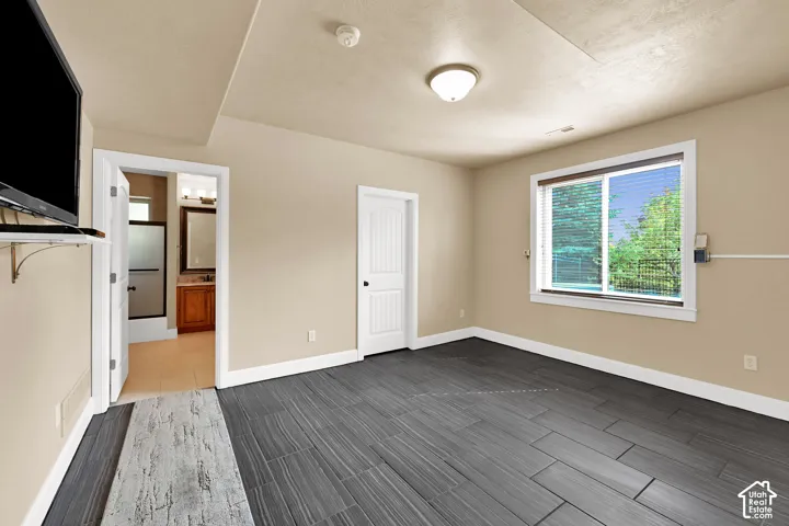 Room featuring tile flooring with a linear grain pattern, neutral-toned wall paint, white trim detailing, and a multi-pane sliding window