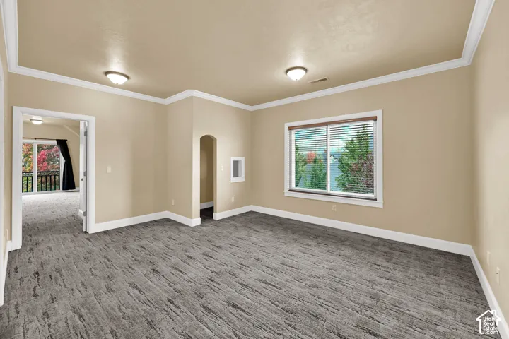 Interior space featuring wood-finish flooring, crown molding, a recessed arched doorway, and double-pane window with exterior natural scenery