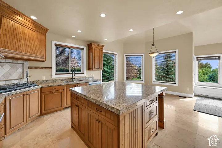 Kitchen featuring stone-topped central island, , stone  flooring, recessed lighting, and multiple windows
