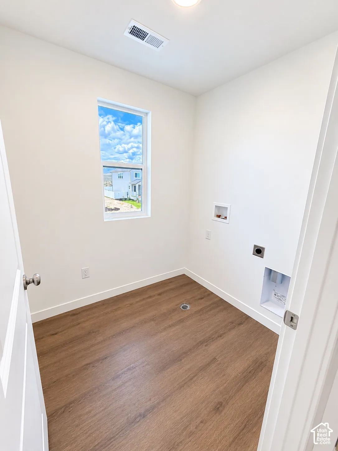 Utility room featuring wood-finish flooring, a vertical window, and dedicated washer and dryer hookups