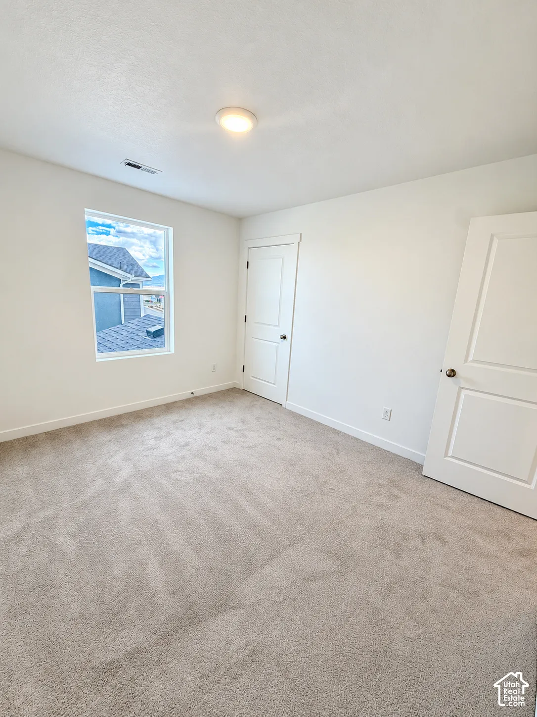 Neutral-toned wall-to-wall carpeting, two-panel interior doors, and a flush-mount ceiling light fixture