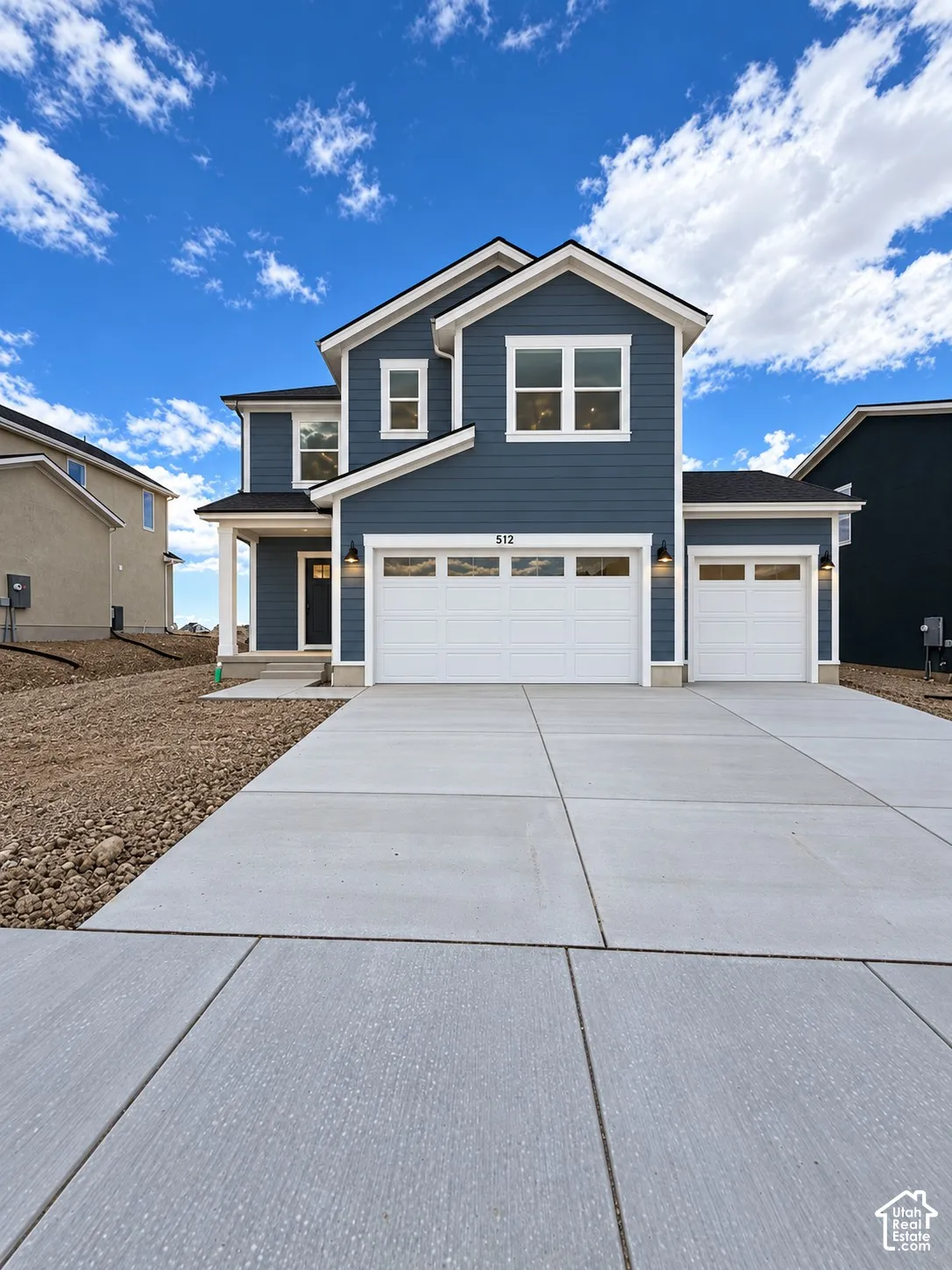 Two-story exterior featuring blue siding with white trim, a concrete driveway, and a three-car garage with white paneled doors