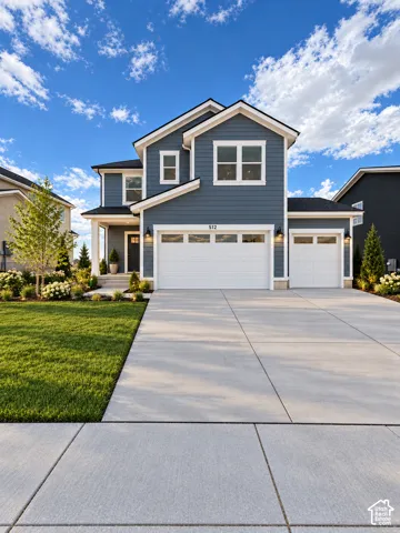Two-story exterior featuring blue siding, white trim, a three-car garage, concrete driveway, and manicured landscaping