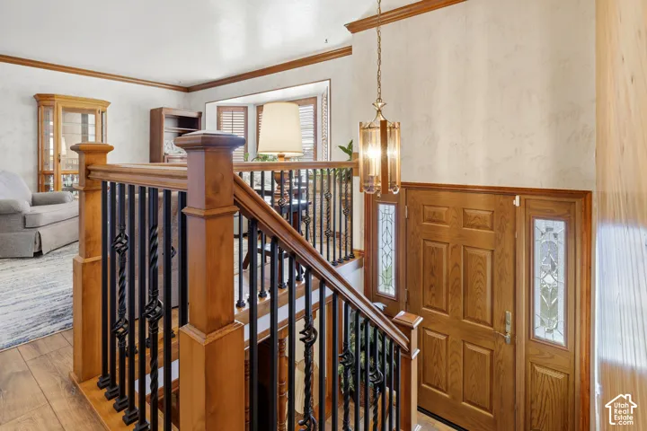 Entryway featuring a wood-panel door with decorative glass side lights, wood-finish railing with metal balusters, and a hanging pendant fixture