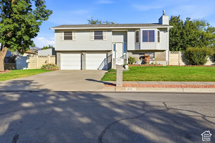 Split-level exterior featuring horizontal siding, an attached two-car garage, a bay window, and decorative shutters