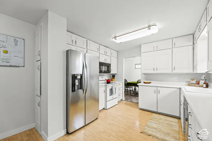Kitchen featuring white cabinetry, wood-finish flooring, stainless steel side-by-side refrigerator, built-in microwave, and recessed ceiling lighting