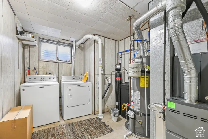 Utility room featuring a water heater, water filtration system, furnace, and a sliding window