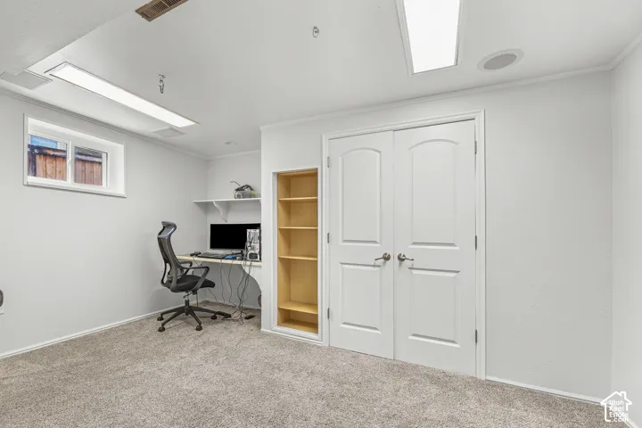 Room featuring carpeted flooring, double doors with arched detailing, integrated shelving, built-in desk surface, and recessed lighting