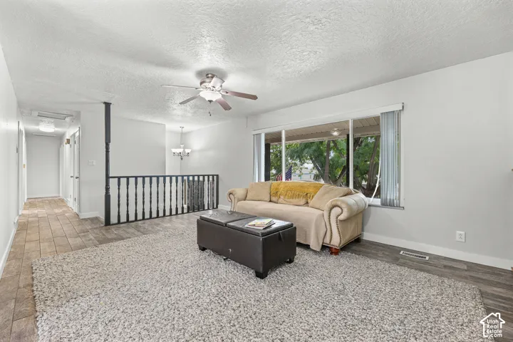 Living area featuring large windows, wood-finish flooring, a ceiling fan, and decorative railings