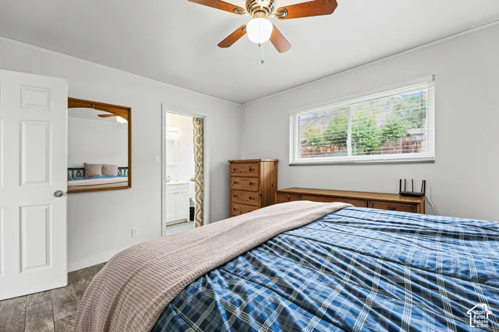 Room featuring wood-finish flooring, a ceiling fan with integrated lighting, a sliding window with horizontal blinds, and a wall-mounted mirror