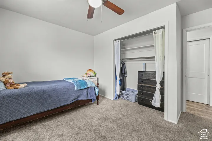 Room featuring neutral carpeting, a ceiling fan with integrated lighting, and a closet with built-in shelving