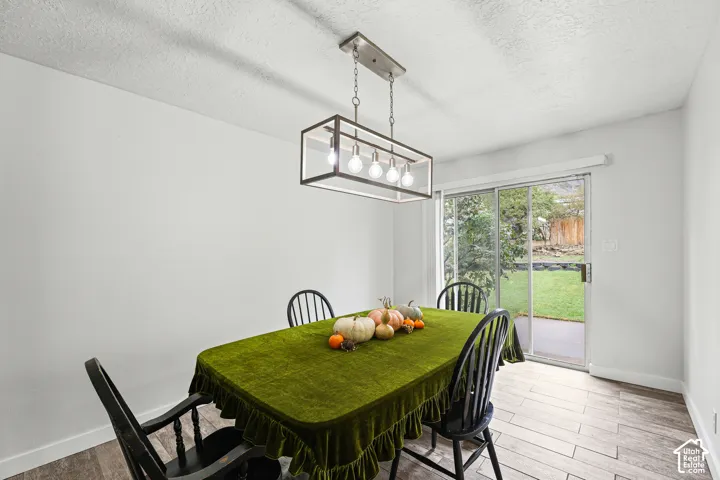 Dining area featuring wood-finish flooring, a contemporary rectangular pendant light fixture with five exposed bulbs, and a sliding glass door providing external access